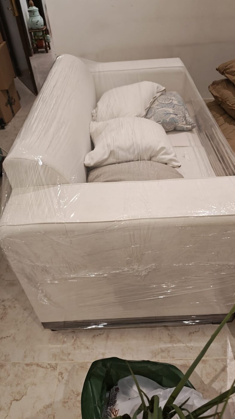 كنبة بيضاء مغلفة بعناية داخل المنزل